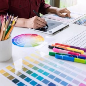 Image of female creative graphic designer working on color selection and drawing on graphics tablet at workplace.